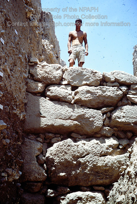 Fld I; Volunteer standing atop boulder courses of Bronze Age wall; to right is burned collapsed mud-brick form upper courses. (1967, ID: cColepGezer081, Source: slide, Repository: NPAPH-project, Creator(s): Dan P. Cole)