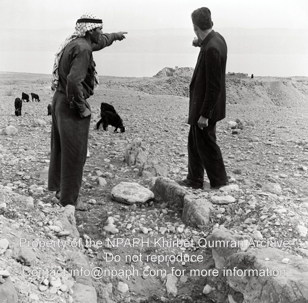 Photo looking to the west from the aqueduct. Journalist Jan Glissenaar is talking to a shepherd at the aqueduct located between the hills and the ruins (31 Dec 1953; ID: cPennartspQumran8; Source: photo; Depository: NPAPH; Creator(s): Peter Pennarts)